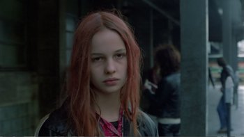 Movie still from “Christiane F.” (1981), directed by Uli Edel – A girl with red hair is standing outside; Close Up shot, Over the shoulder angle