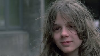Movie still from “Christiane F.” (1981), directed by Uli Edel – A young girl with long hair is posing for a picture; Close Up shot, Over the shoulder angle