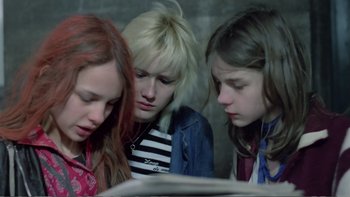 Movie still from “Christiane F.” (1981), directed by Uli Edel – A group of young people looking at a book; Medium shot, High angle