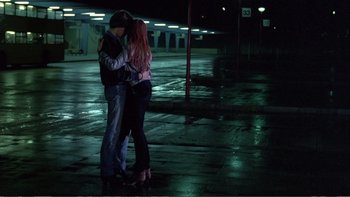 Movie still from “Christiane F.” (1981), directed by Uli Edel – A man and a woman kissing in a parking lot at night; Wide shot, Low angle
