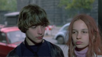 Movie still from “Christiane F.” (1981), directed by Uli Edel – A boy and a girl standing next to each other on the street; Close Up shot, Over the shoulder angle