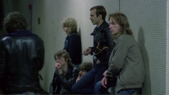 Movie still from “Christiane F.” (1981), directed by Uli Edel – A group of people sitting in a room next to each other; Medium shot, High angle