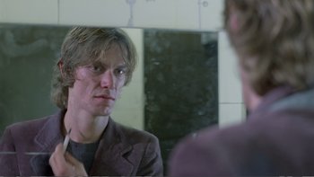 Movie still from “Christiane F.” (1981), directed by Uli Edel – A man looking at himself in the mirror in front of a bathroom mirror; Close Up shot, Over the shoulder angle