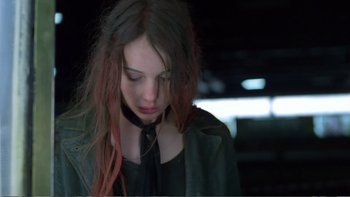 Movie still from “Christiane F.” (1981), directed by Uli Edel – A woman with long hair and a black shirt is looking down; Close Up shot, High angle
