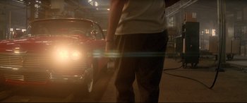 Movie still from “Christine” (1983), directed by John Carpenter – A man standing in front of a car in a garage; Wide shot, Low angle