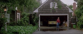 Movie still from “Christine” (1983), directed by John Carpenter – A man standing in front of a car parked in a garage; Wide shot, Low angle