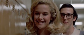 Movie still from “Christine” (1983), directed by John Carpenter – A person with blonde hair smiling; Close Up shot, Low angle
