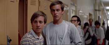 Movie still from “Christine” (1983), directed by John Carpenter – Two young men standing next to each other in a hallway; Medium shot, Low angle