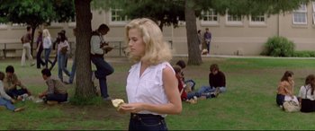 Movie still from “Christine” (1983), directed by John Carpenter – A woman in a white shirt is holding an apple; Wide shot, High angle