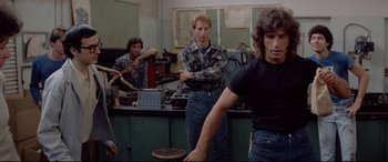 Movie still from “Christine” (1983), directed by John Carpenter – A group of men standing in front of a table; Medium shot, Low angle