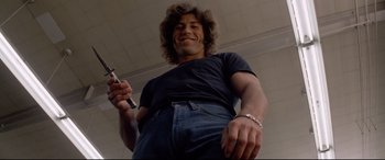 Movie still from “Christine” (1983), directed by John Carpenter – A man holding a cell phone in his hand; Medium shot, Low angle