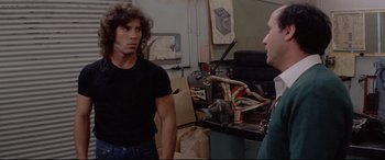Movie still from “Christine” (1983), directed by John Carpenter – Two men are standing in front of a table; Medium shot, Over the shoulder angle