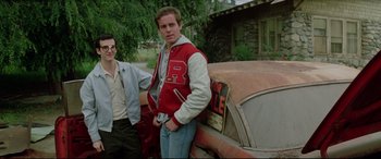 Movie still from “Christine” (1983), directed by John Carpenter – A man and a woman standing next to an old car; Medium shot, Low angle