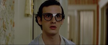 Movie still from “Christine” (1983), directed by John Carpenter – A young man wearing a pair of glasses looking surprised; Close Up shot, Low angle