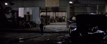 Movie still from “Christine” (1983), directed by John Carpenter – A person walking in front of a garage; Extreme Wide shot, High angle