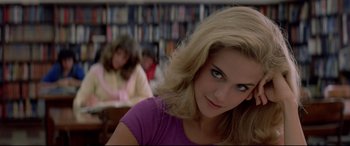 Movie still from “Christine” (1983), directed by John Carpenter – A woman in a purple shirt in front of a book shelf; Close Up shot, Low angle