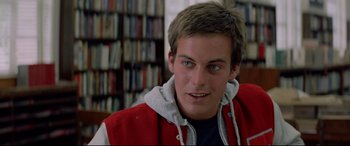 Movie still from “Christine” (1983), directed by John Carpenter – A young man in a red and white jacket is smiling; Close Up shot, Over the shoulder angle