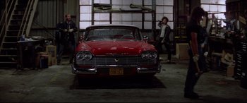 Movie still from “Christine” (1983), directed by John Carpenter – An old red car is parked in a garage; Wide shot, Low angle