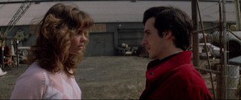 Movie still from “Christine” (1983), directed by John Carpenter – A man and a woman standing next to each other; Close Up shot, Low angle