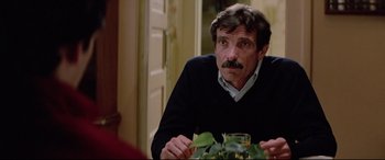 Movie still from “Christine” (1983), directed by John Carpenter – A person sitting at a table; Close Up shot, Over the shoulder angle