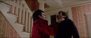 Movie still from “Christine” (1983), directed by John Carpenter – Two men in red jackets one of them is pulling the other on his neck; Close Up shot, High angle