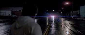 Movie still from “Christine” (1983), directed by John Carpenter – A man standing in the middle of a road at night; Extreme Wide shot, Over the shoulder angle