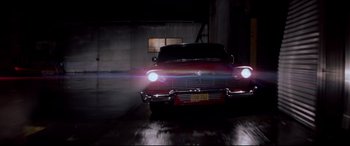 Movie still from “Christine” (1983), directed by John Carpenter – A red car is driving down the street; Wide shot, Low angle