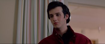 Movie still from “Christine” (1983), directed by John Carpenter – A young man in a red jacket looks to his left; Close Up shot, Low angle