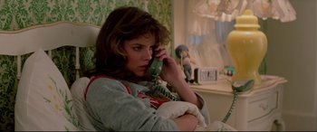 Movie still from “Christine” (1983), directed by John Carpenter – A woman sitting in a chair talking on a phone; Medium shot, High angle