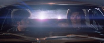 Movie still from “Christine” (1983), directed by John Carpenter – Two people in a car looking out the window at the sun; Close Up shot, Low angle