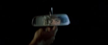 Movie still from “Christine” (1983), directed by John Carpenter – A man looking into a rear view mirror of a car; Extreme Close Up shot, Over the shoulder angle