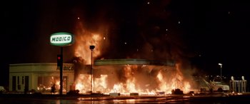 Movie still from “Christine” (1983), directed by John Carpenter – A large fire burning in a parking lot at night; Extreme Wide shot, Low angle