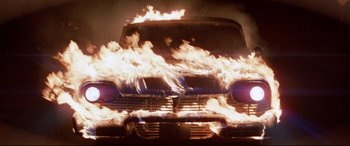 Movie still from “Christine” (1983), directed by John Carpenter – A car that is on fire in the dark; Wide shot, Low angle