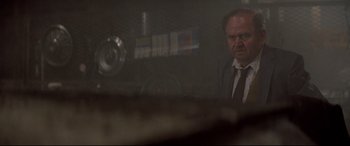 Movie still from “Christine” (1983), directed by John Carpenter – A man wearing a suit and tie in front of a mirror; Medium shot, Low angle