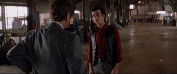 Movie still from “Christine” (1983), directed by John Carpenter – A man in a red shirt is talking to another man in a gray suit; Medium shot, Over the shoulder angle