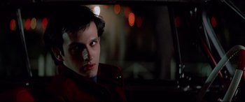 Movie still from “Christine” (1983), directed by John Carpenter – A young man sitting in the back seat of a car at night; Close Up shot, Low angle