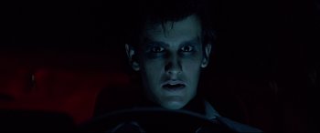 Movie still from “Christine” (1983), directed by John Carpenter – A young man is driving in the dark at night; Close Up shot, Low angle