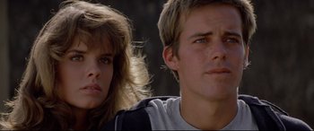 Movie still from “Christine” (1983), directed by John Carpenter – A man and a woman standing next to each other in front of trees; Close Up shot, Low angle