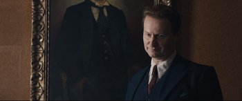 Movie still from “Christopher Robin” (2018), directed by Marc Forster – A man in a suit and tie standing next to a suit; Medium shot, Over the shoulder angle