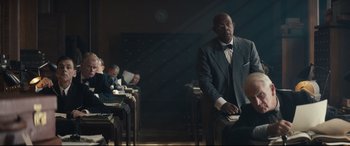 Movie still from “Christopher Robin” (2018), directed by Marc Forster – A man standing in front of a group of people; Medium shot, Over the shoulder angle