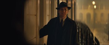 Movie still from “Christopher Robin” (2018), directed by Marc Forster – A man wearing a hat and a suit standing next to a door; Medium shot, Over the shoulder angle