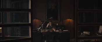 Movie still from “Christopher Robin” (2018), directed by Marc Forster – A man sitting at a desk in front of a painting; Wide shot, Low angle