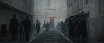Movie still from “Christopher Robin” (2018), directed by Marc Forster – A group of people walking down a street with a red telephone booth; Extreme Wide shot, High angle