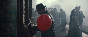 Movie still from “Christopher Robin” (2018), directed by Marc Forster – A man in a black hat is holding a red balloon; Medium shot, Low angle