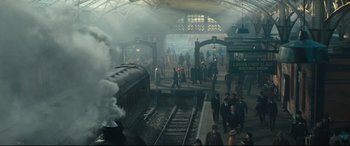 Movie still from “Christopher Robin” (2018), directed by Marc Forster – A train station with people walking on the tracks and steam coming out of the station; Extreme Wide shot, High angle