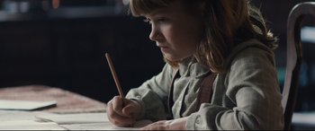 Movie still from “Christopher Robin” (2018), directed by Marc Forster – A little girl is writing with a wooden pencil; Close Up shot, High angle