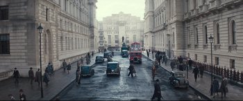 Movie still from “Christopher Robin” (2018), directed by Marc Forster – A group of people walking down a street with cars; Extreme Wide shot, High angle