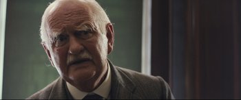 Movie still from “Christopher Robin” (2018), directed by Marc Forster – An old man with a beard and mustache wearing a suit and tie; Close Up shot, Over the shoulder angle