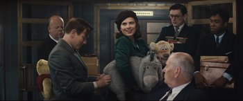 Movie still from “Christopher Robin” (2018), directed by Marc Forster – A group of people sitting around each other holding stuffed animals; Medium shot, Over the shoulder angle