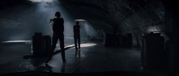 Movie still from “Chrysalis” (2007), directed by Julien Leclercq – Two people standing under an umbrella in the dark; Wide shot, Low angle